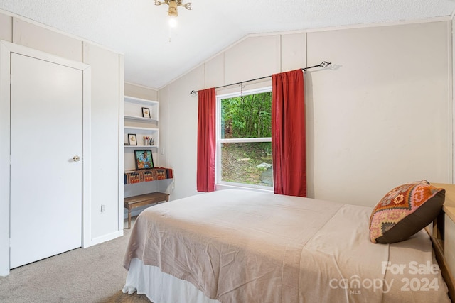 carpeted bedroom featuring a textured ceiling and lofted ceiling