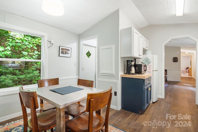 dining area with hardwood / wood-style flooring, a textured ceiling, and lofted ceiling