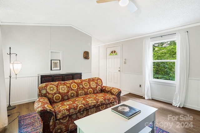 living room with ornamental molding, wood-type flooring, a textured ceiling, ceiling fan, and lofted ceiling