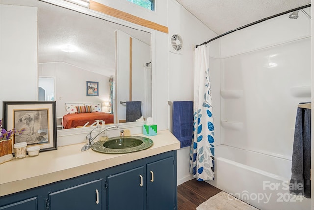 bathroom featuring vanity, wood-type flooring, shower / tub combo, a textured ceiling, and lofted ceiling