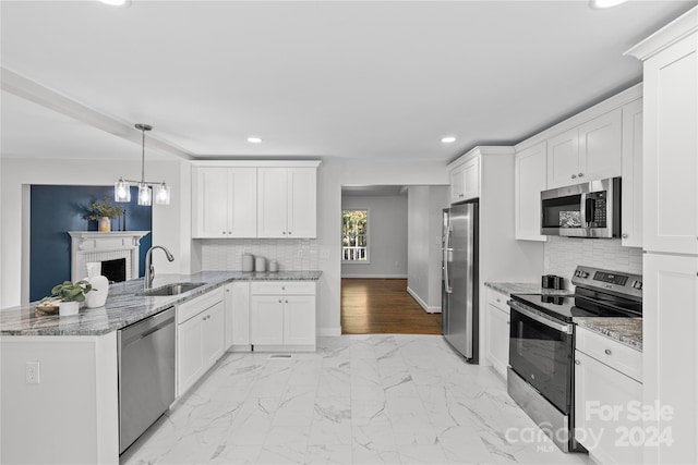 kitchen featuring appliances with stainless steel finishes, sink, kitchen peninsula, white cabinetry, and decorative light fixtures