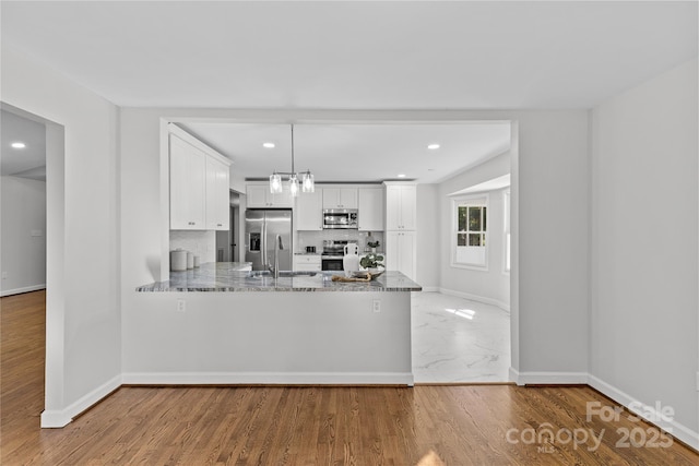 kitchen with sink, stone countertops, kitchen peninsula, stainless steel appliances, and white cabinets