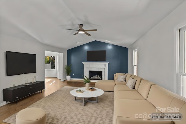 living room featuring hardwood / wood-style flooring, ceiling fan, a fireplace, and vaulted ceiling