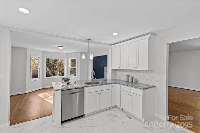 kitchen featuring pendant lighting, sink, white cabinetry, stainless steel dishwasher, and kitchen peninsula