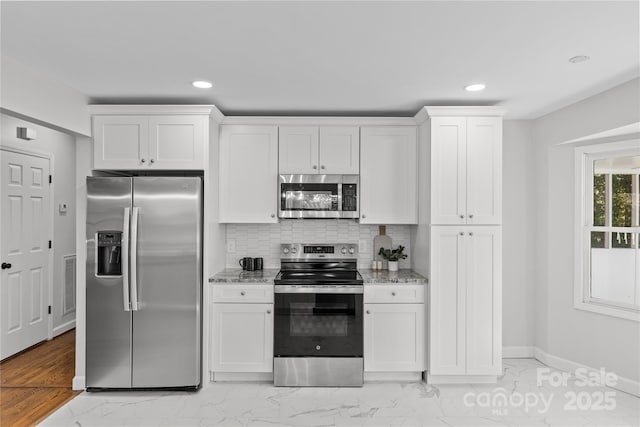 kitchen with stainless steel appliances, white cabinets, light stone counters, and decorative backsplash