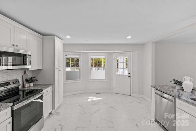 kitchen featuring stainless steel appliances, white cabinetry, light stone countertops, and a wealth of natural light