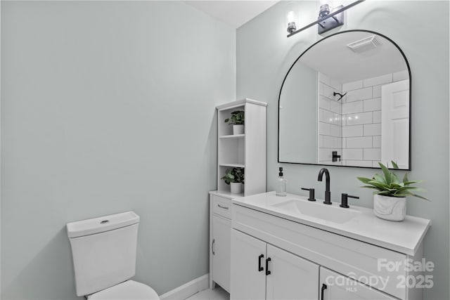 bathroom with tiled shower, vanity, and toilet