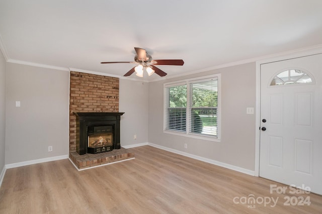 unfurnished living room featuring baseboards, ornamental molding, a fireplace, and light wood-style floors