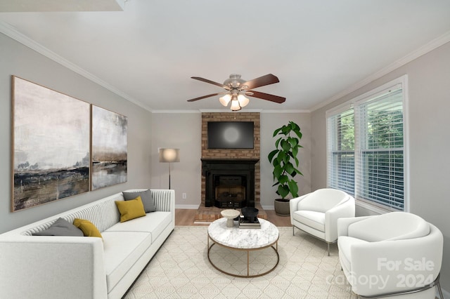 living room with light wood finished floors, ornamental molding, a fireplace, and a ceiling fan