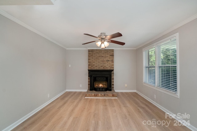 unfurnished living room featuring a brick fireplace, baseboards, crown molding, and light wood finished floors