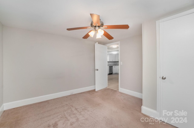 empty room featuring ceiling fan, baseboards, and light colored carpet