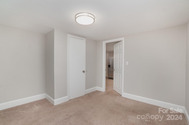 spare room featuring light carpet and baseboards