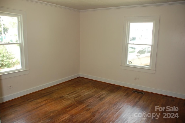 empty room featuring ornamental molding and dark hardwood / wood-style flooring