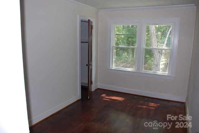 unfurnished room featuring visible vents, baseboards, wood finished floors, and crown molding