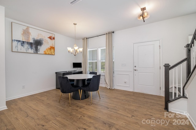 dining room with baseboards, visible vents, wood finished floors, an inviting chandelier, and stairs