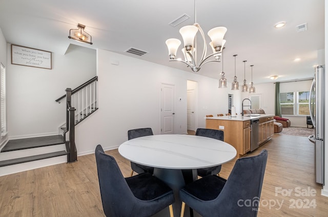 dining room with light wood-style flooring, visible vents, and stairway