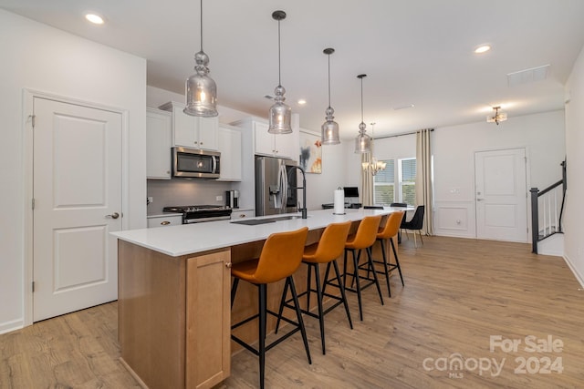 kitchen with decorative backsplash, a spacious island, appliances with stainless steel finishes, light wood-type flooring, and a sink