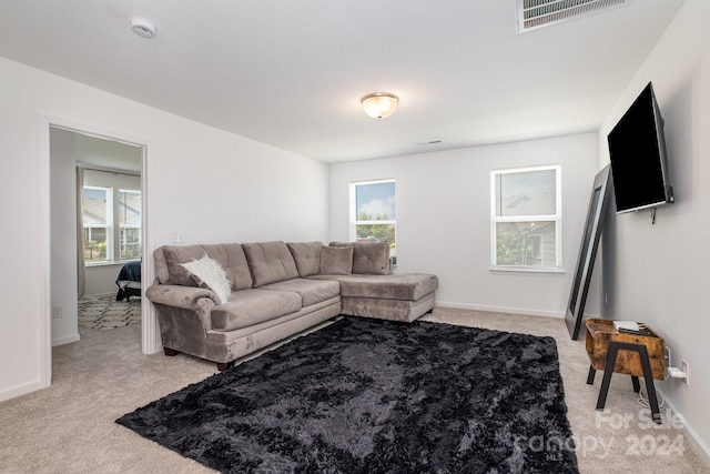 living room with light carpet, a wealth of natural light, visible vents, and baseboards