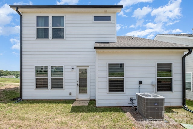 back of property with central AC, a lawn, and roof with shingles