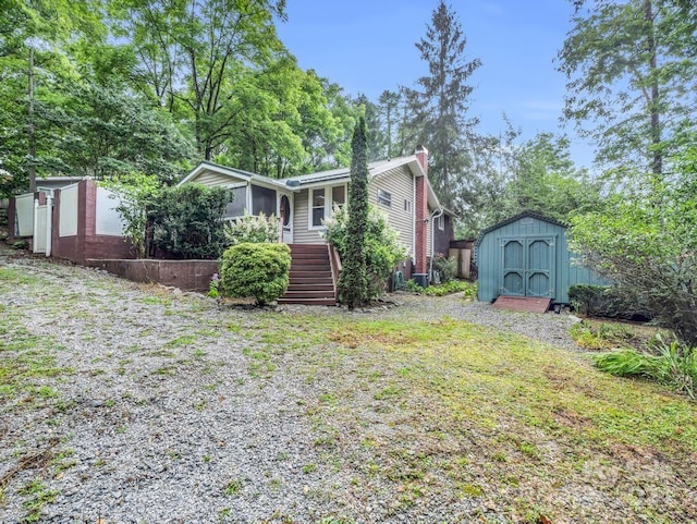 view of front of house with a storage shed, stairs, a chimney, and an outdoor structure