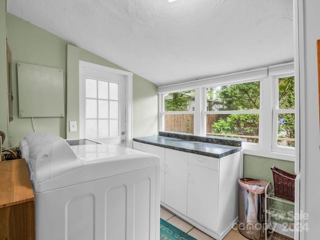 kitchen with lofted ceiling, dark countertops, white cabinetry, a textured ceiling, and washer / dryer