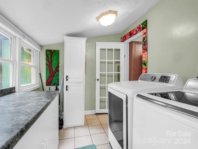 washroom featuring cabinet space, a textured ceiling, washing machine and clothes dryer, and light tile patterned floors