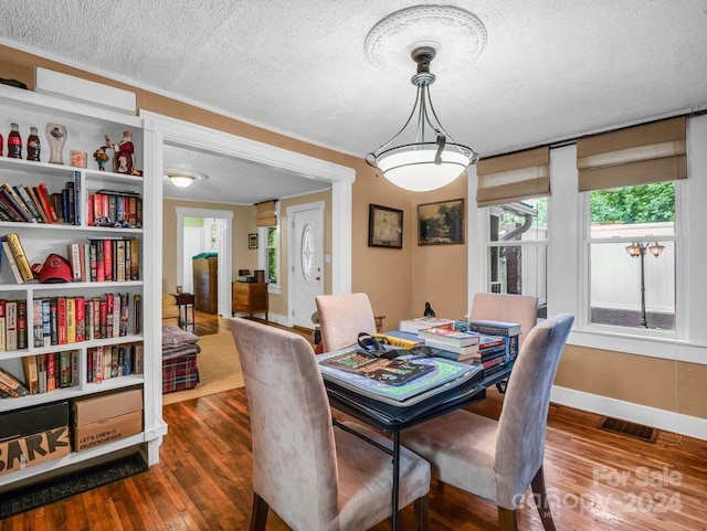 dining space featuring a textured ceiling, wood-type flooring, visible vents, and baseboards