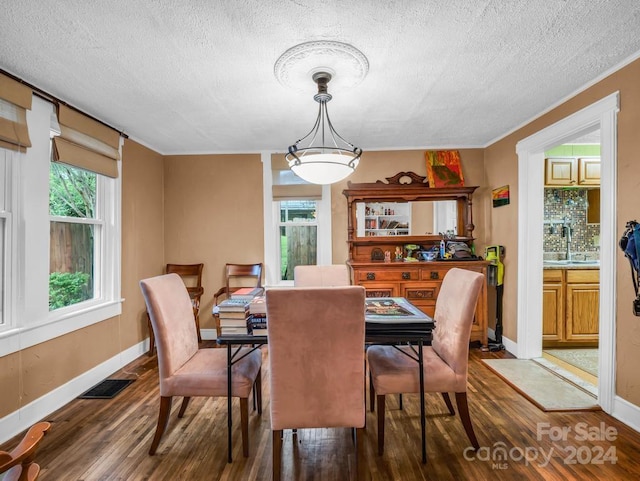 dining room featuring visible vents, a textured ceiling, baseboards, and wood finished floors