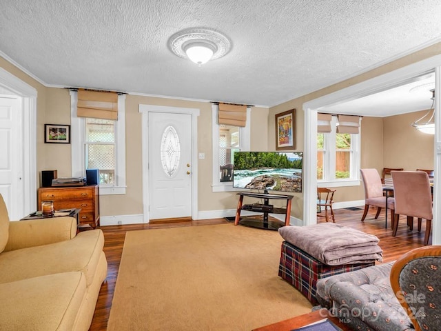 entryway with a textured ceiling, baseboards, wood finished floors, and ornamental molding