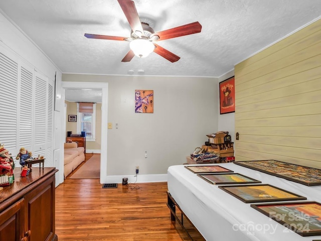 bedroom featuring a closet, a textured ceiling, baseboards, and wood finished floors