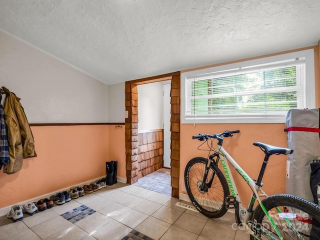 workout area with baseboards, a textured ceiling, and tile patterned floors