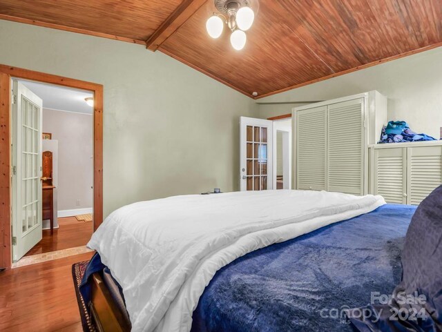 bedroom with lofted ceiling with beams, wooden ceiling, baseboards, and wood finished floors