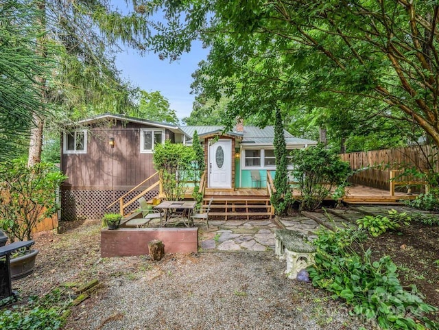 view of front of property with entry steps, metal roof, a deck, fence, and a patio area