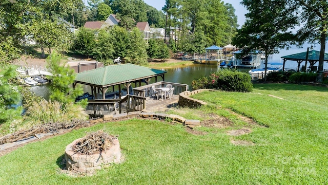 dock area featuring a fire pit, a yard, a deck with water view, and a gazebo