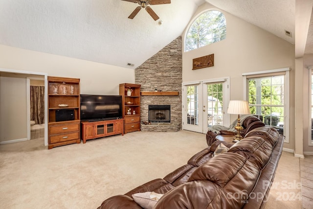 carpeted living room featuring a fireplace, a textured ceiling, high vaulted ceiling, and ceiling fan