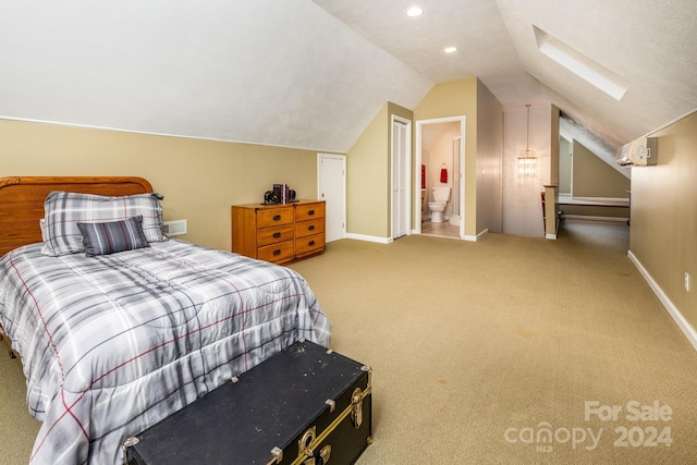 bedroom featuring light carpet, ensuite bathroom, and lofted ceiling with skylight