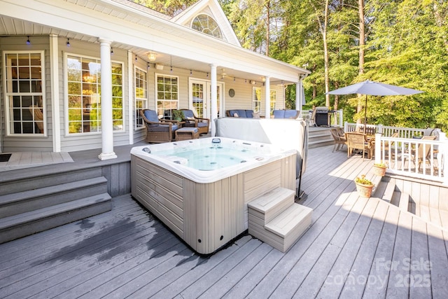 wooden terrace featuring outdoor dining space and a hot tub