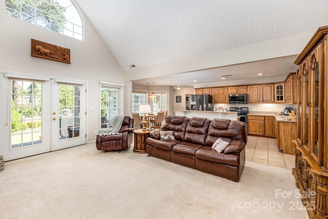 living area featuring light colored carpet, visible vents, french doors, and high vaulted ceiling