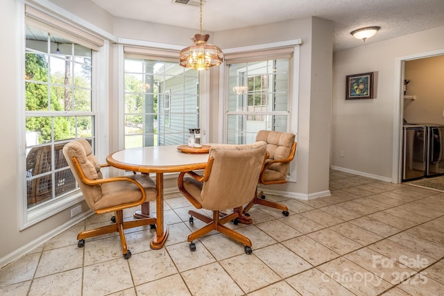 dining room featuring a textured ceiling, washing machine and clothes dryer, baseboards, a notable chandelier, and visible vents