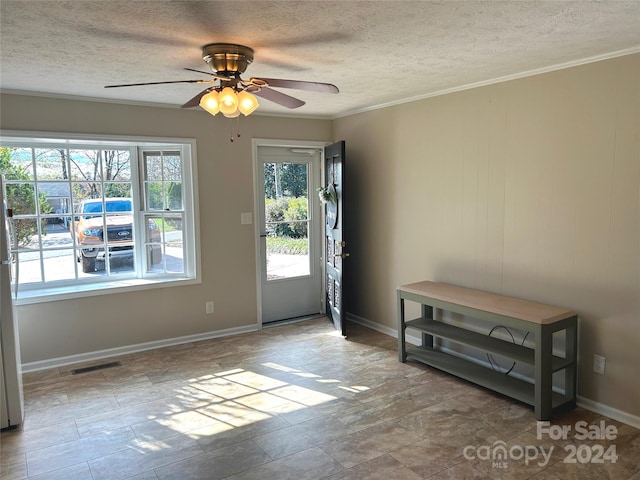 entryway with a textured ceiling, ceiling fan, and crown molding