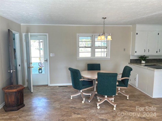 dining space with a chandelier, a textured ceiling, and ornamental molding