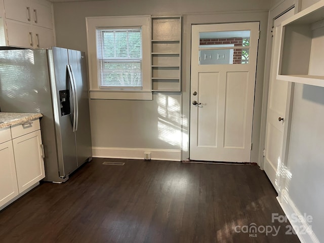 kitchen with dark wood-type flooring, stainless steel fridge, and white cabinets