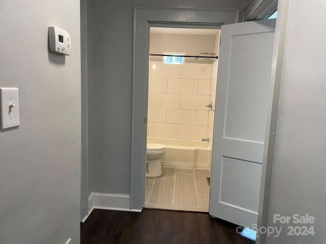 bathroom with toilet, tiled shower / bath, and hardwood / wood-style flooring