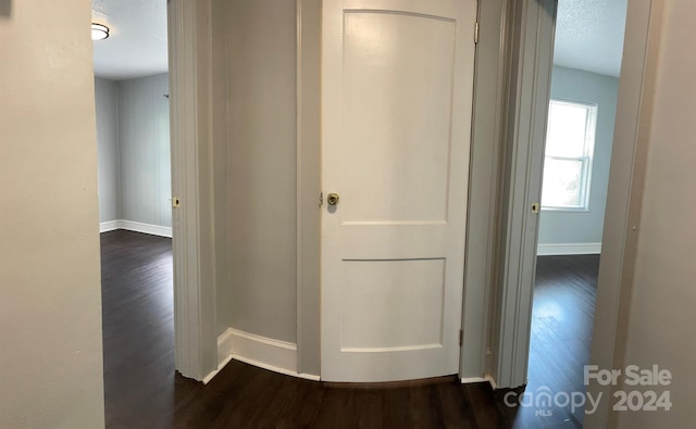 corridor with dark wood-type flooring and a textured ceiling