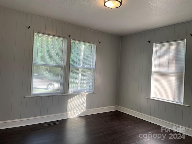 spare room with a textured ceiling and dark wood-type flooring