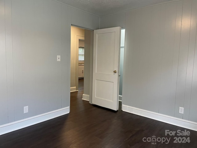 unfurnished room featuring a textured ceiling and dark hardwood / wood-style flooring