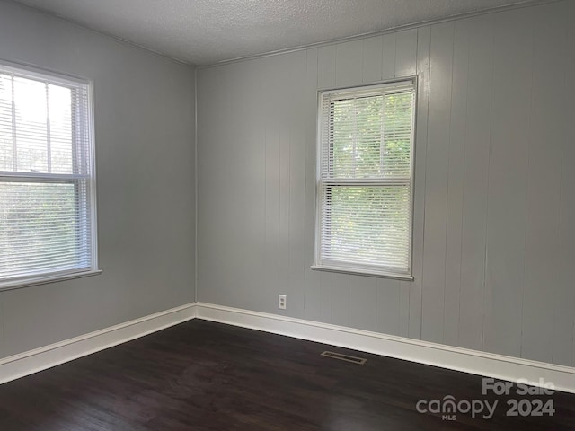 unfurnished room featuring a textured ceiling and dark hardwood / wood-style floors