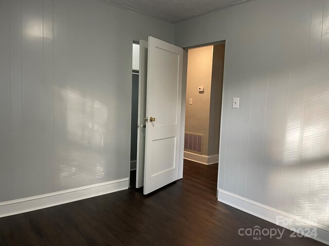 spare room featuring a textured ceiling and dark wood-type flooring