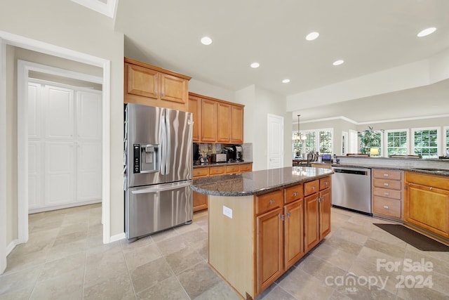 kitchen with recessed lighting, stainless steel appliances, a kitchen island, backsplash, and dark stone counters