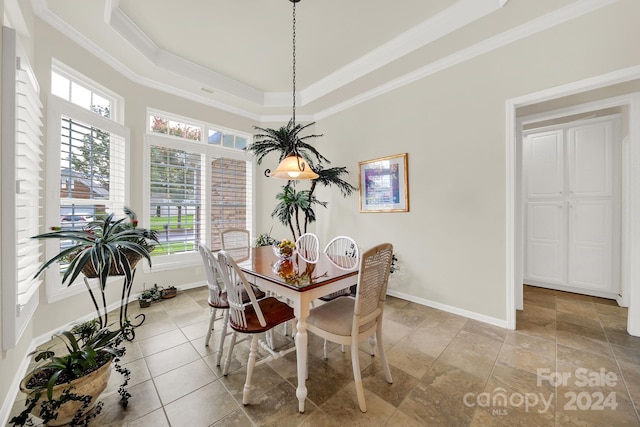 dining space featuring crown molding, light tile patterned flooring, and a tray ceiling